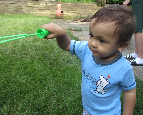 Trying to dip his bubble wand into the mixture