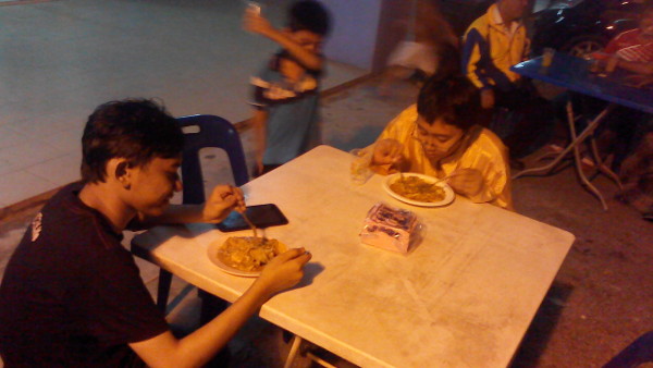 Irfan and his brother's friend enjoy some char kuey teow.